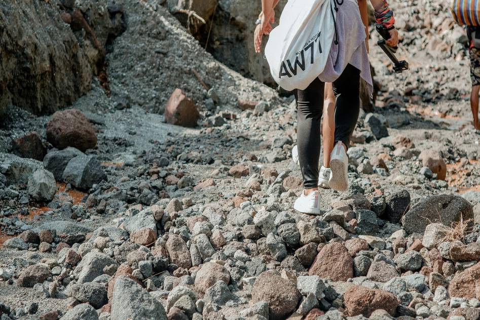 Backpack-style surfboard carrier on rocky coastal path